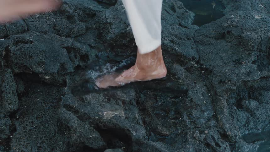 A foot splashes in a small pool of water on dark rocks
