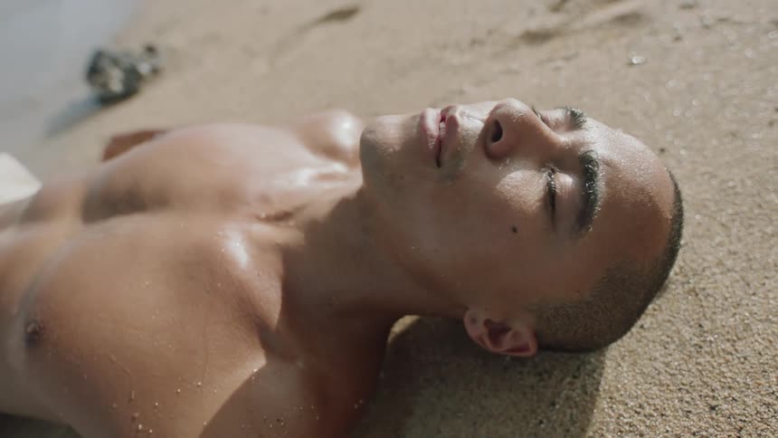 Man lying on the sand of the beach and sea water wetting his body