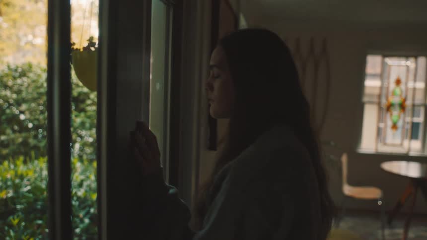 A heartbroken woman leans her forehead against the door