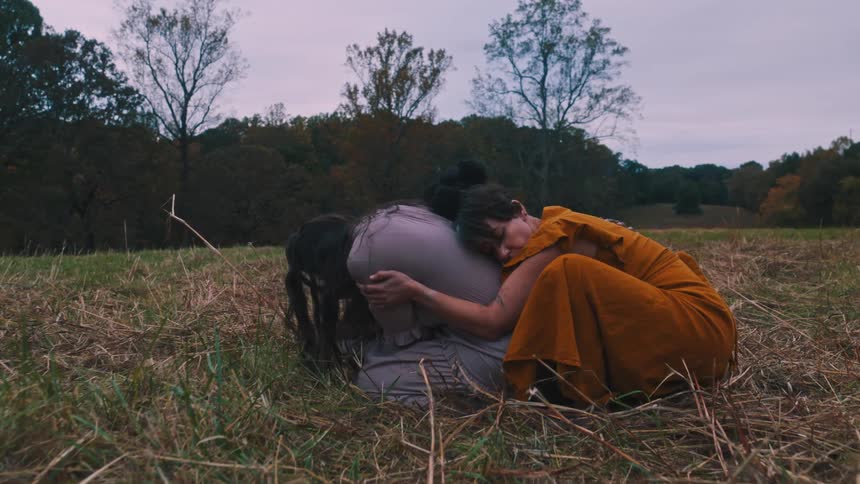 Three women crouched together in a field