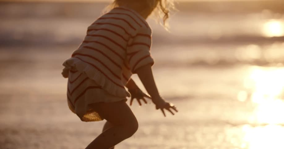 Little girl on the beach with the sunset on the horizon