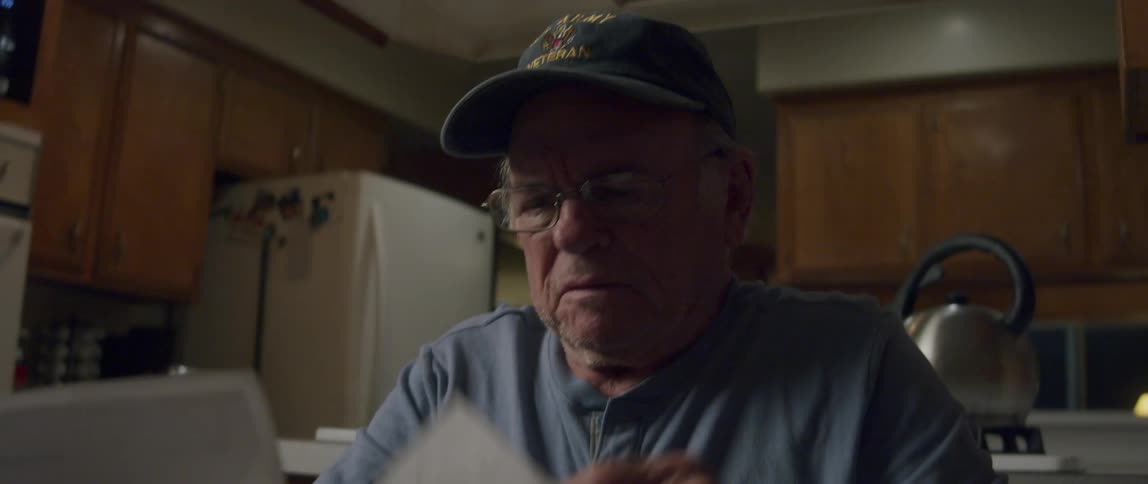 Elderly man sitting reading a letter and being happy