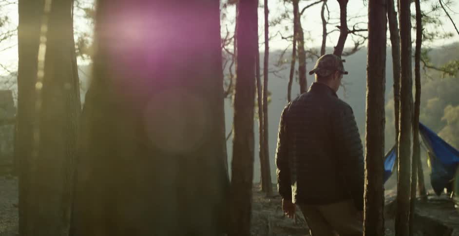 Couple walking through trees towards a couple of hammocks at sunset