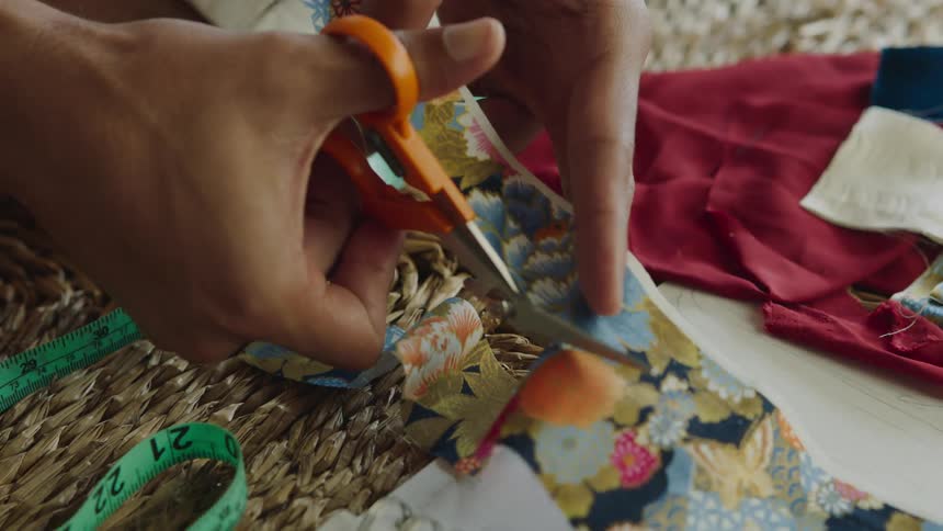 Close up of a persons hand with scissors cutting fabric