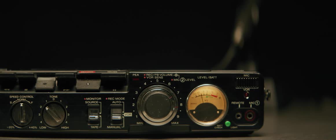 The control panel of a vintage cassette recorder with dials buttons and meters