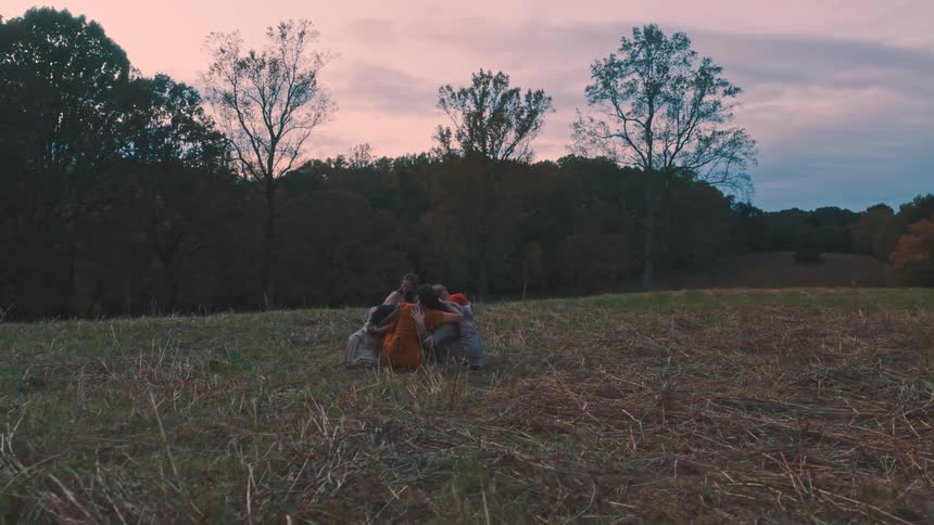 Group of women hugging together in a field in the late afternoon