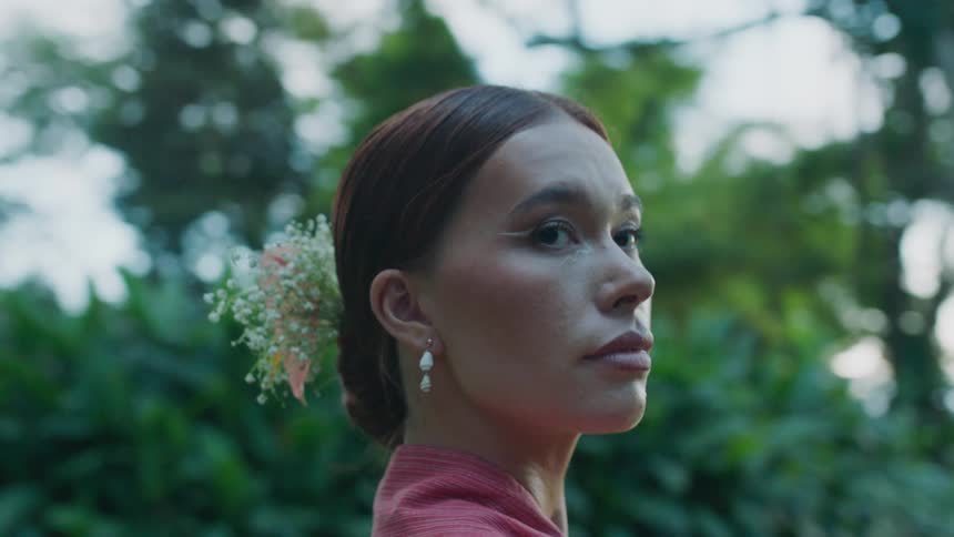 A woman with a floral hair bow looks back at the camera