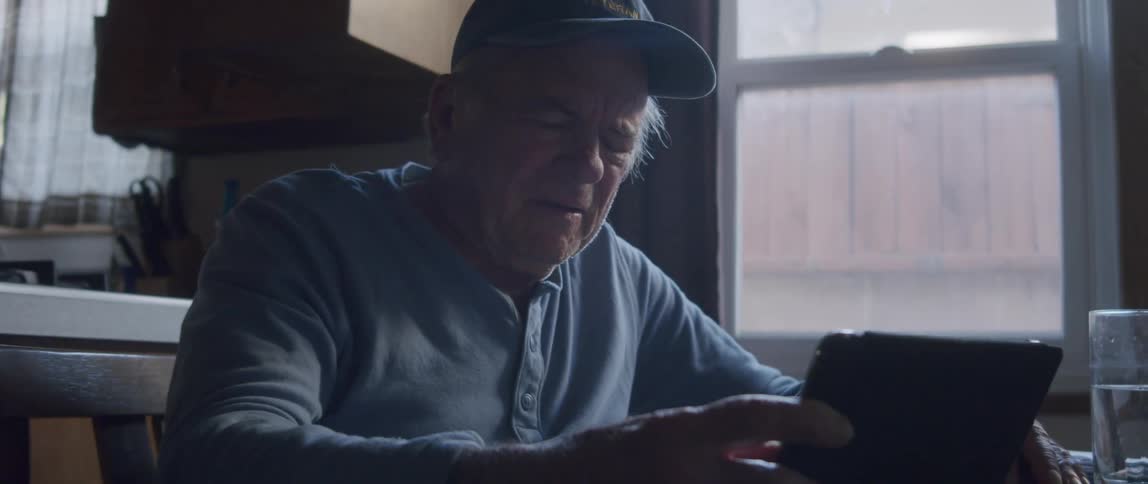 An elderly man looks disappointed as he reads looks at a table