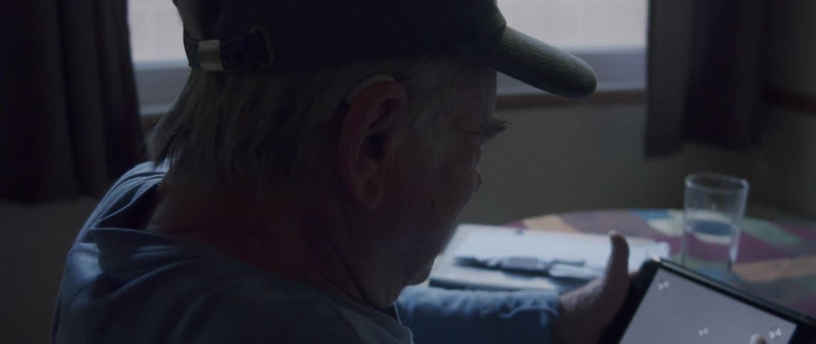 Elderly man sitting on a tablet at the table