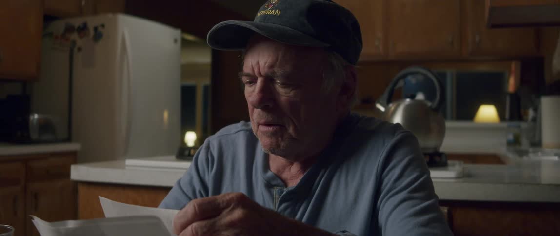 Elderly man sitting at the table and laughing happily after opening a letter