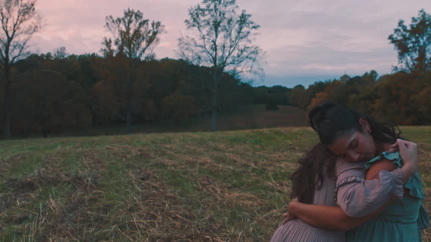 Two women in a field hugging each other