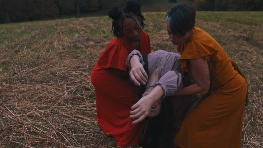 Trio of women in a dance presentation performance in a field