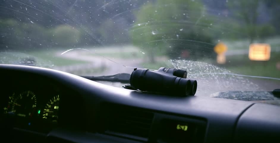 Binoculars sitting on the dashboard of a moving vehicle