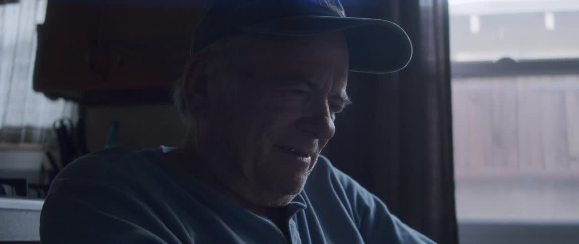 Portrait of an elderly man in a cap sitting with a happy facial expression