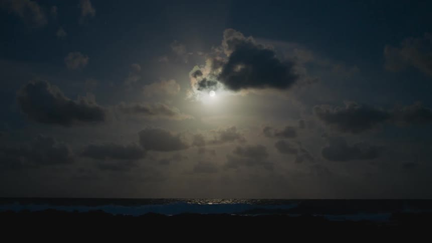 Sun shines brightly through a cloudy sky over a calm ocean below