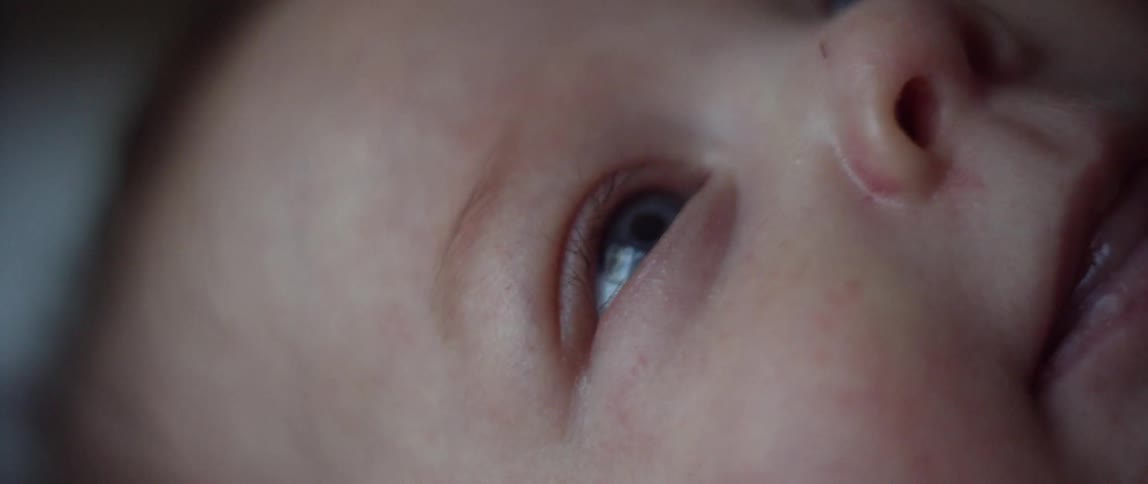 A little baby is moving its tongue while it is looking up