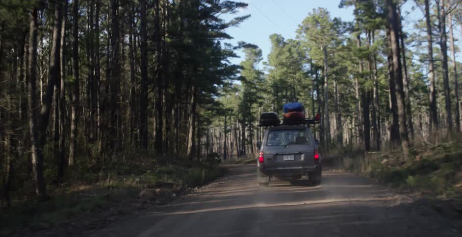 Vehicle loaded with equipment on top driving down a dirt road