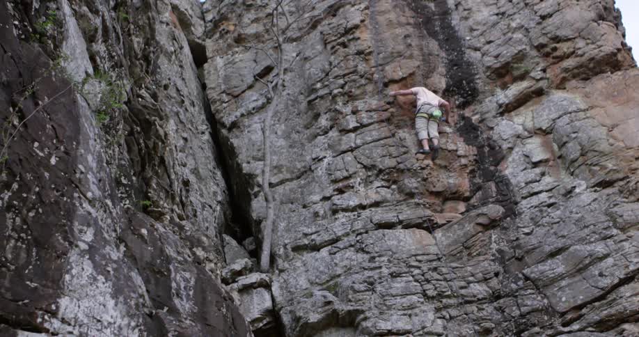 A rock climber making a long step