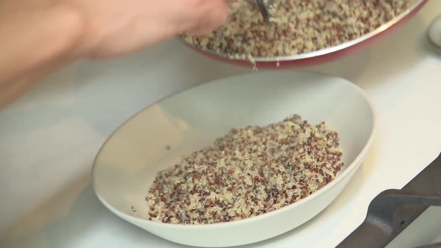 A person serving quinoa into a bowl