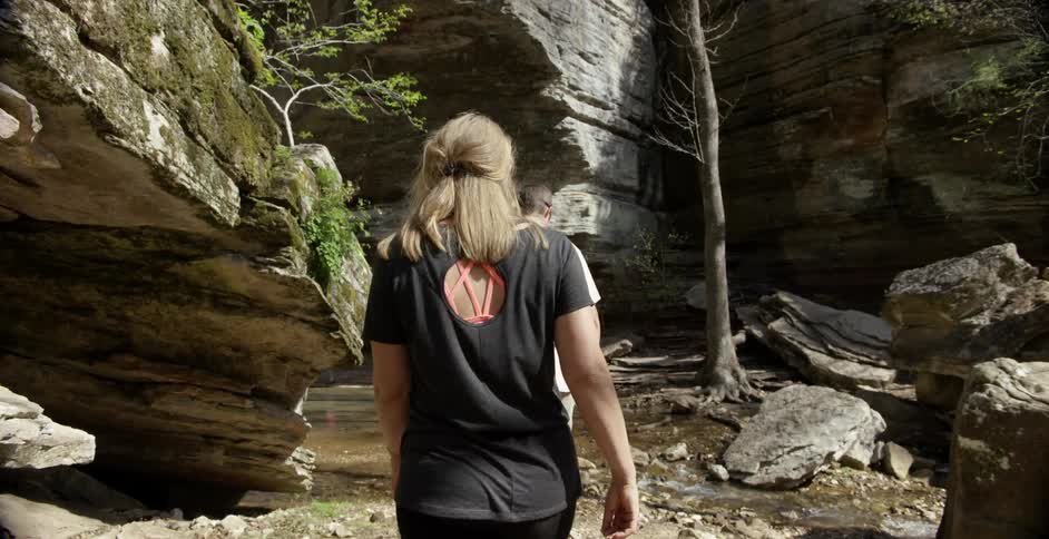 A man and a woman walking along a small stream