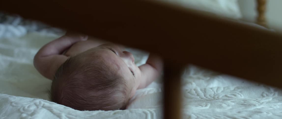 A baby laying in it's crib on it's back