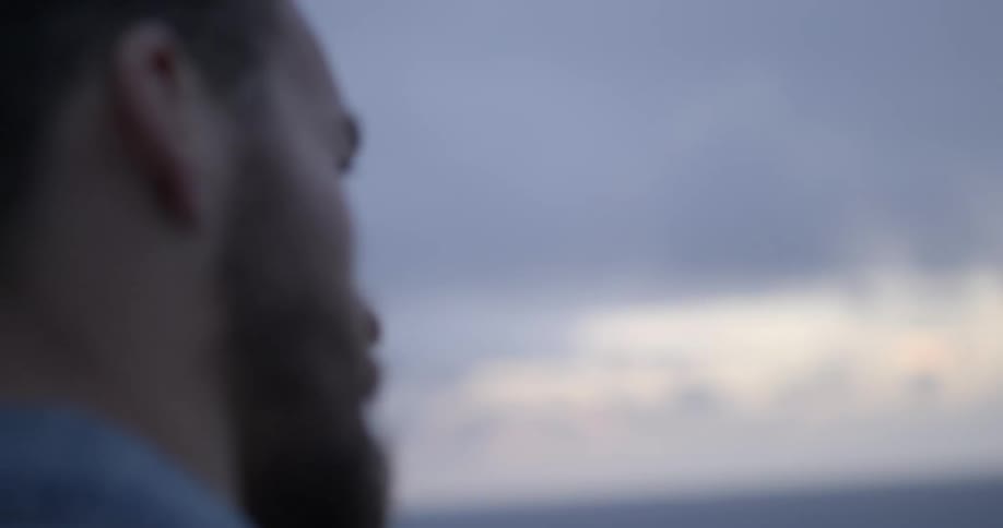A man looks towards the sea at dusk
