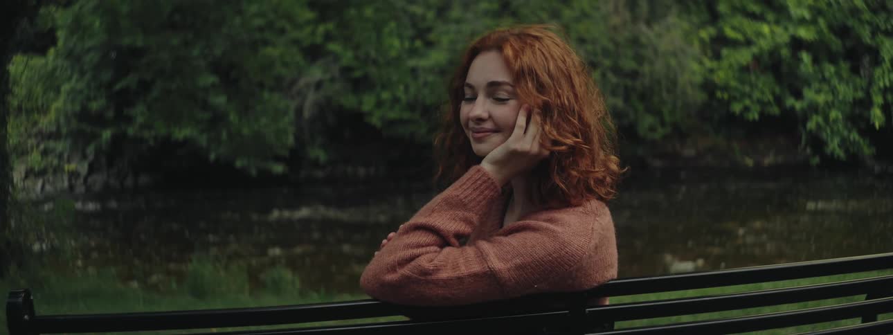 Woman sitting on a bench by a river