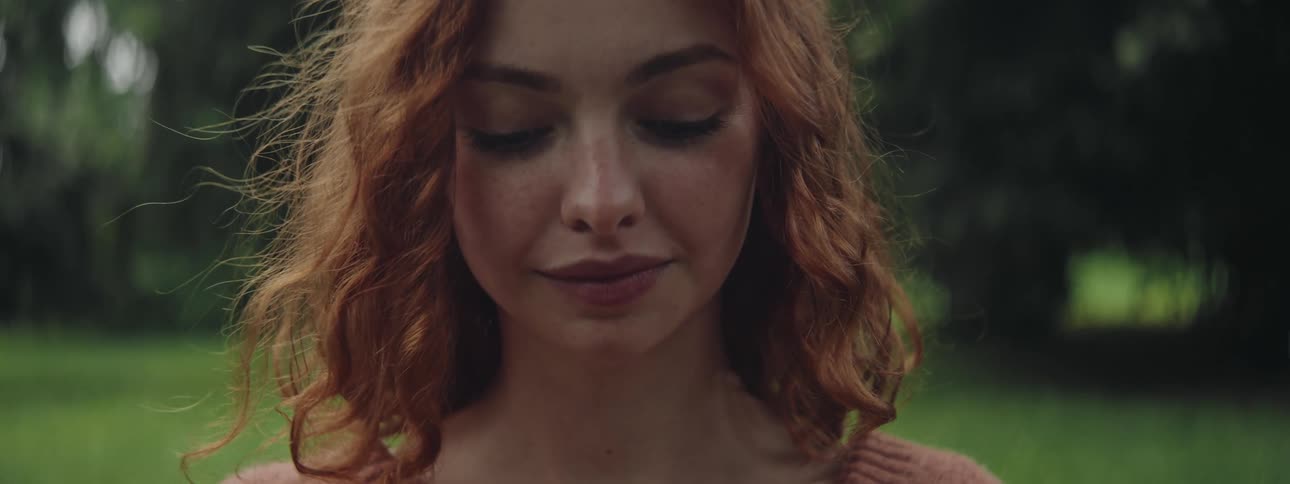 Close up of the face of a young redhead woman stands in a park