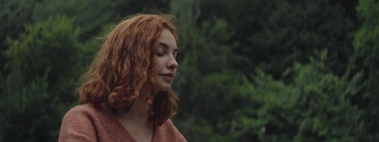 Redhead woman in a natural environment with green trees in the background