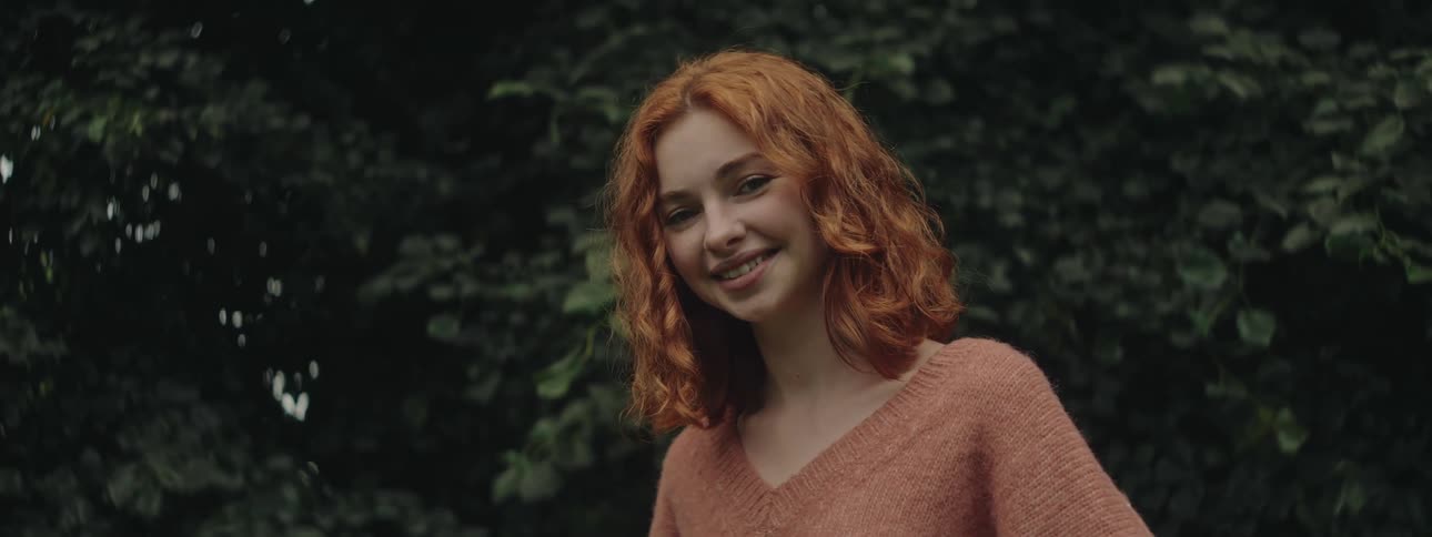 A readheaded young woman smiles for the camera