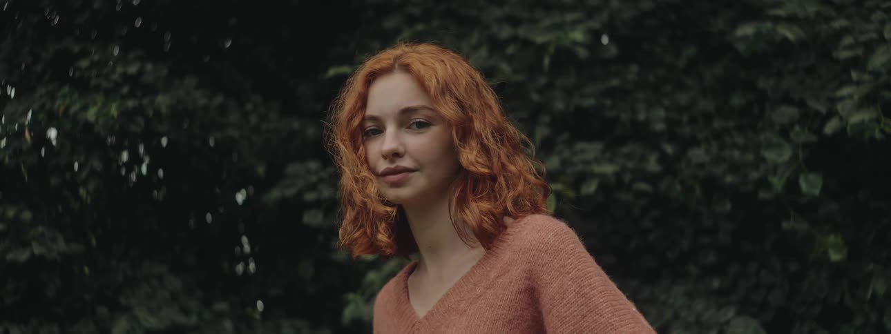 Portrait of a redhaired woman in a natural environment with green tree leaves in the background
