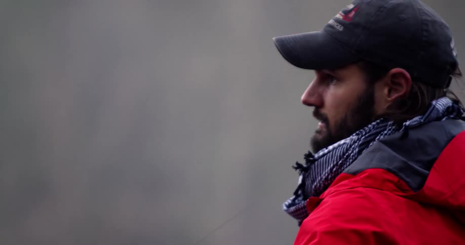 Bearded man in a dark hat casting his fishing line