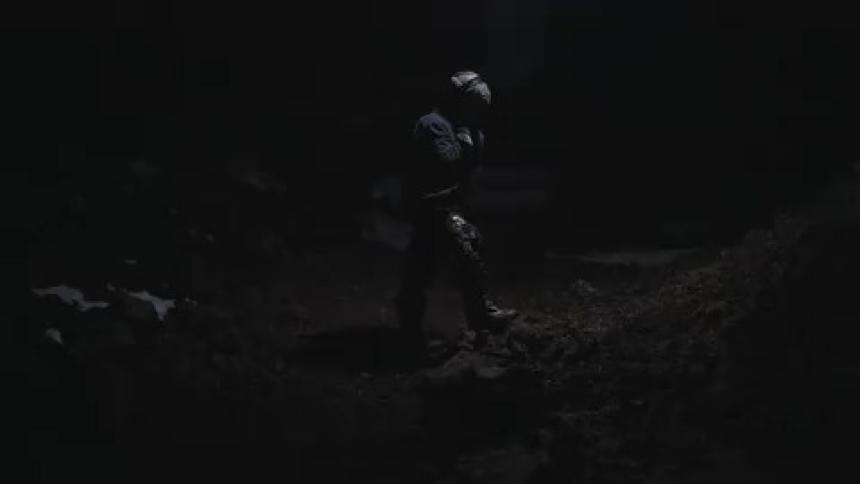 Person wearing a helmet standing in a natural area at night