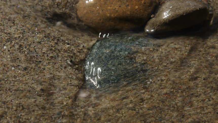 Water flows over the sand and rocks