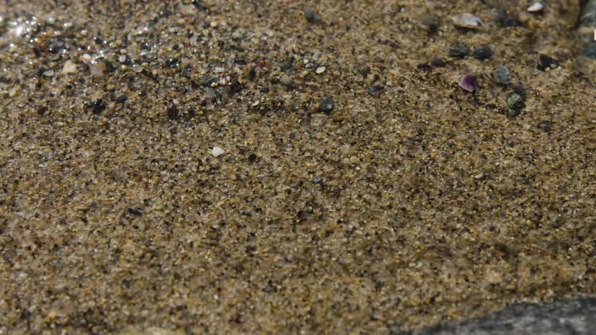 Close up of a water flowing over sand from a shallow stream