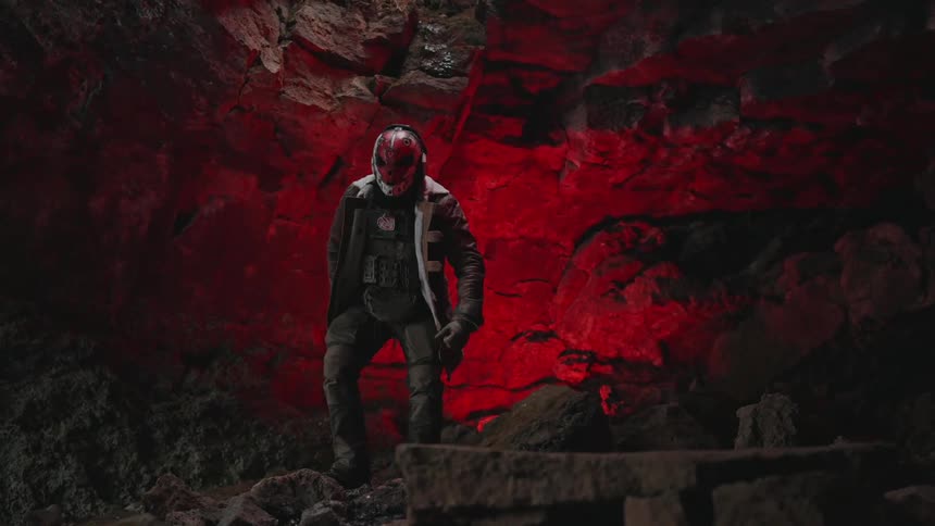 Person with a red mask standing up while in a cave