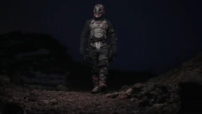 Person wearing mask and vest walking through snowy natural area