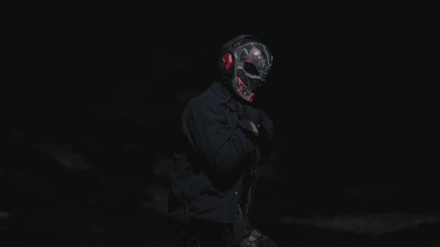 A person wearing dark clothing with a strange mask over their head