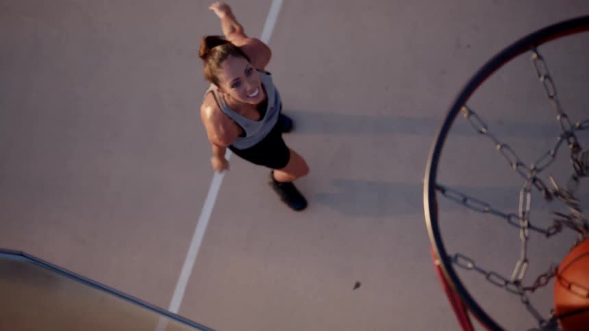 Smiling woman throwing a basketball into the hoop