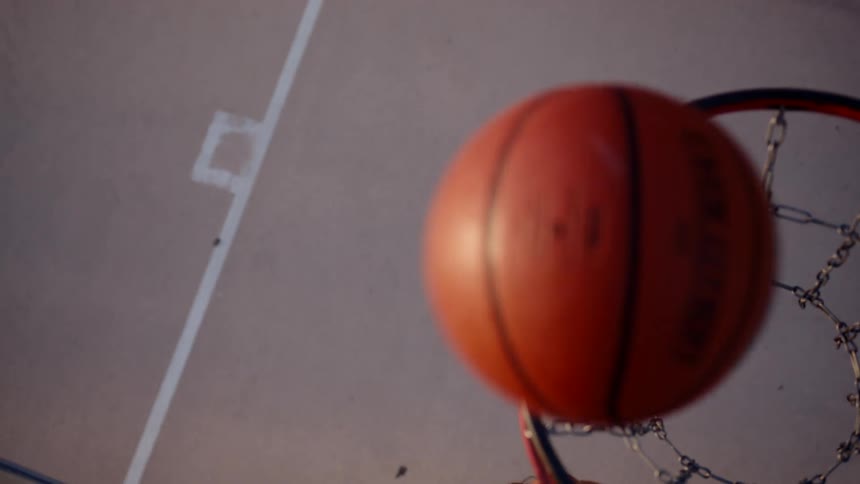 Woman jumping and throwing the basketball towards the basket