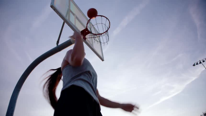 Woman jumping and throwing basketball into hoop