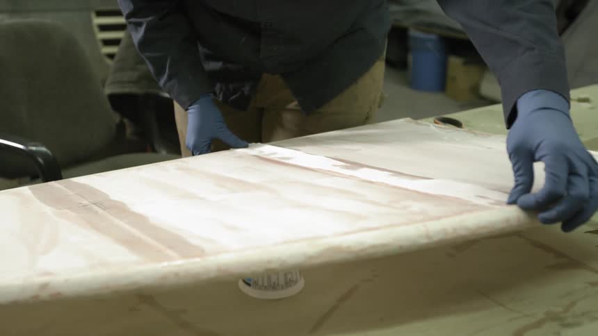 A person is smoothing a strip of tape to white piece of board