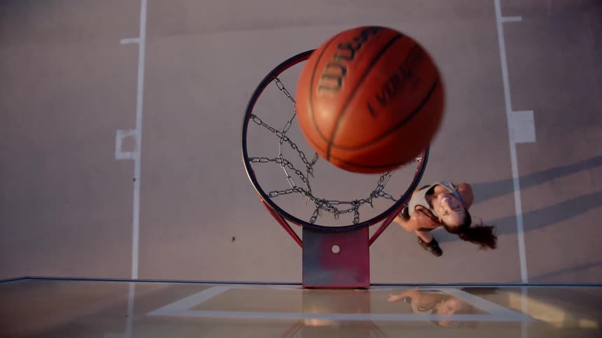 A female basketball player shoots the basketball into the hoop
