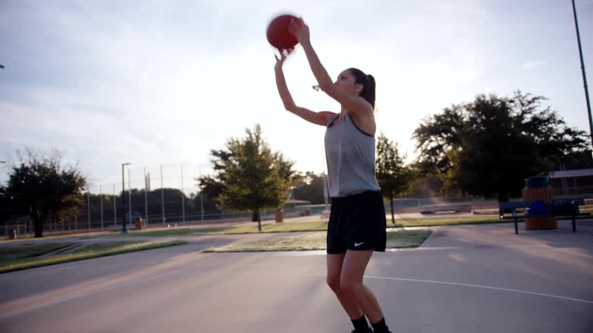 A woman dribbles and shoots the basketball