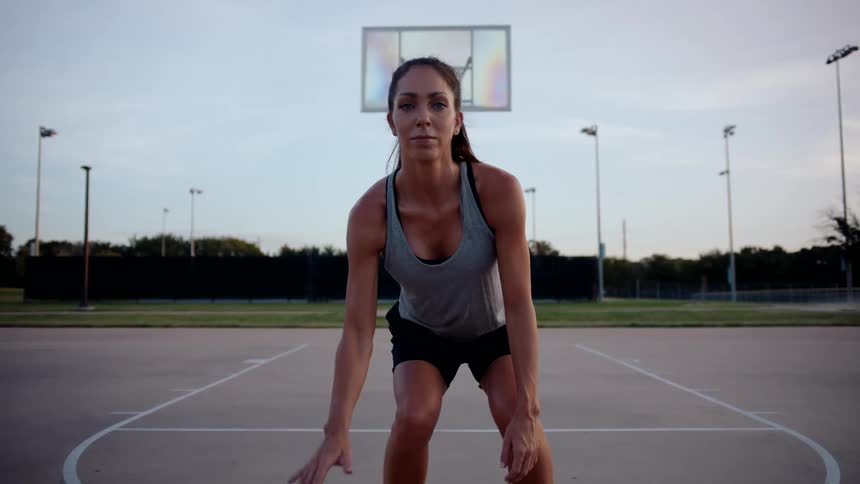 Woman hitting basketball on court