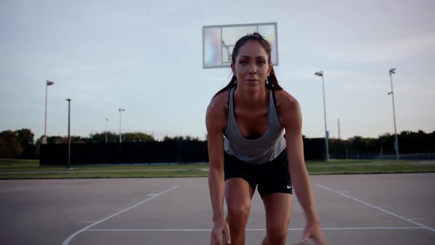 Woman on a court hitting the basketball and dribbling