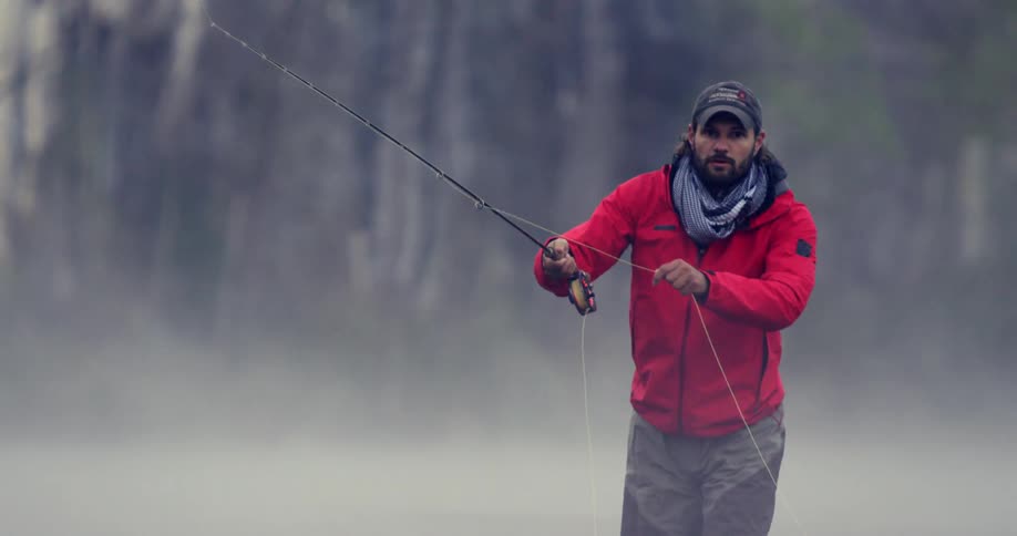 A man casts a fishing line on a misty day