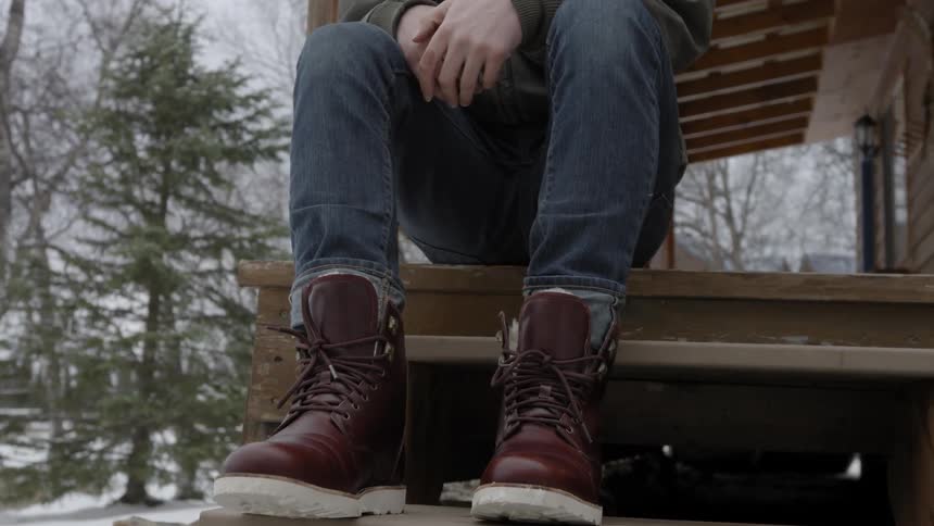 A man sits on a wood front porch