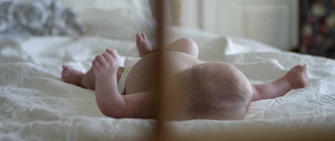 A baby wearing a diaper is lying on its back
