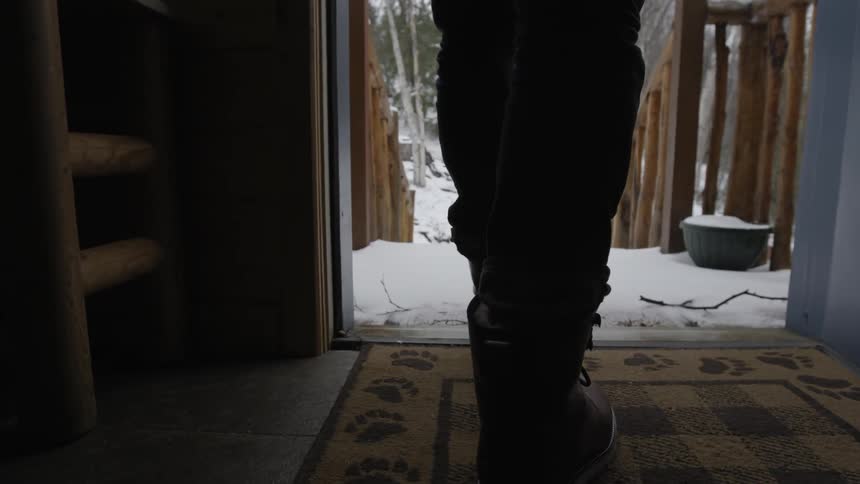 A person walks out the door and down snow covered stairs